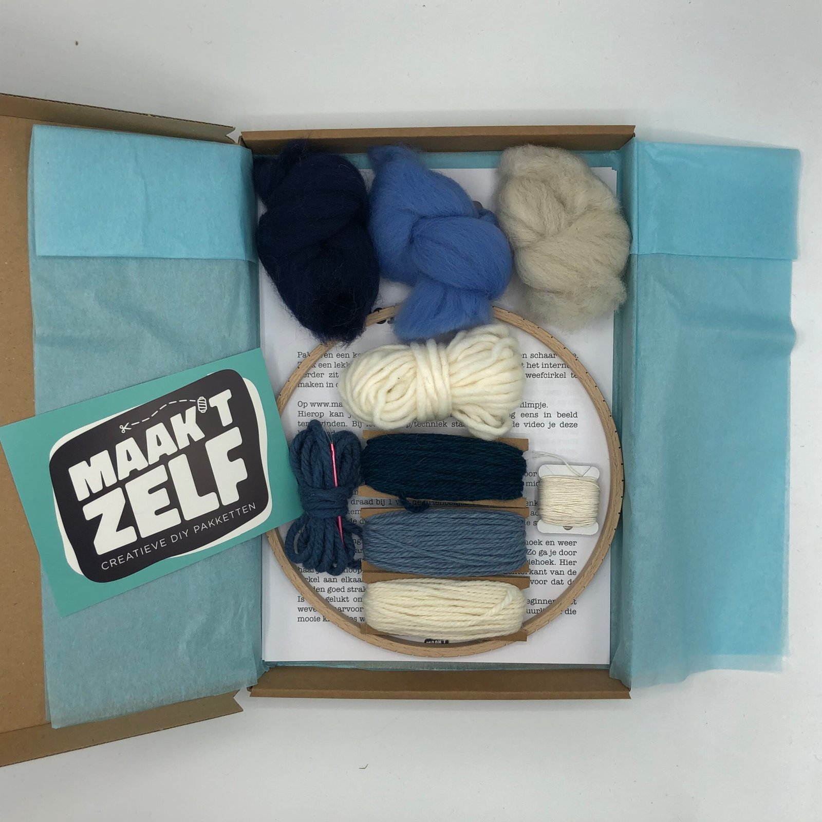 DIY weefpakket met houten weefraam, lontwol in blauw en crème tinten, garen en handleiding van MaakTzelf.