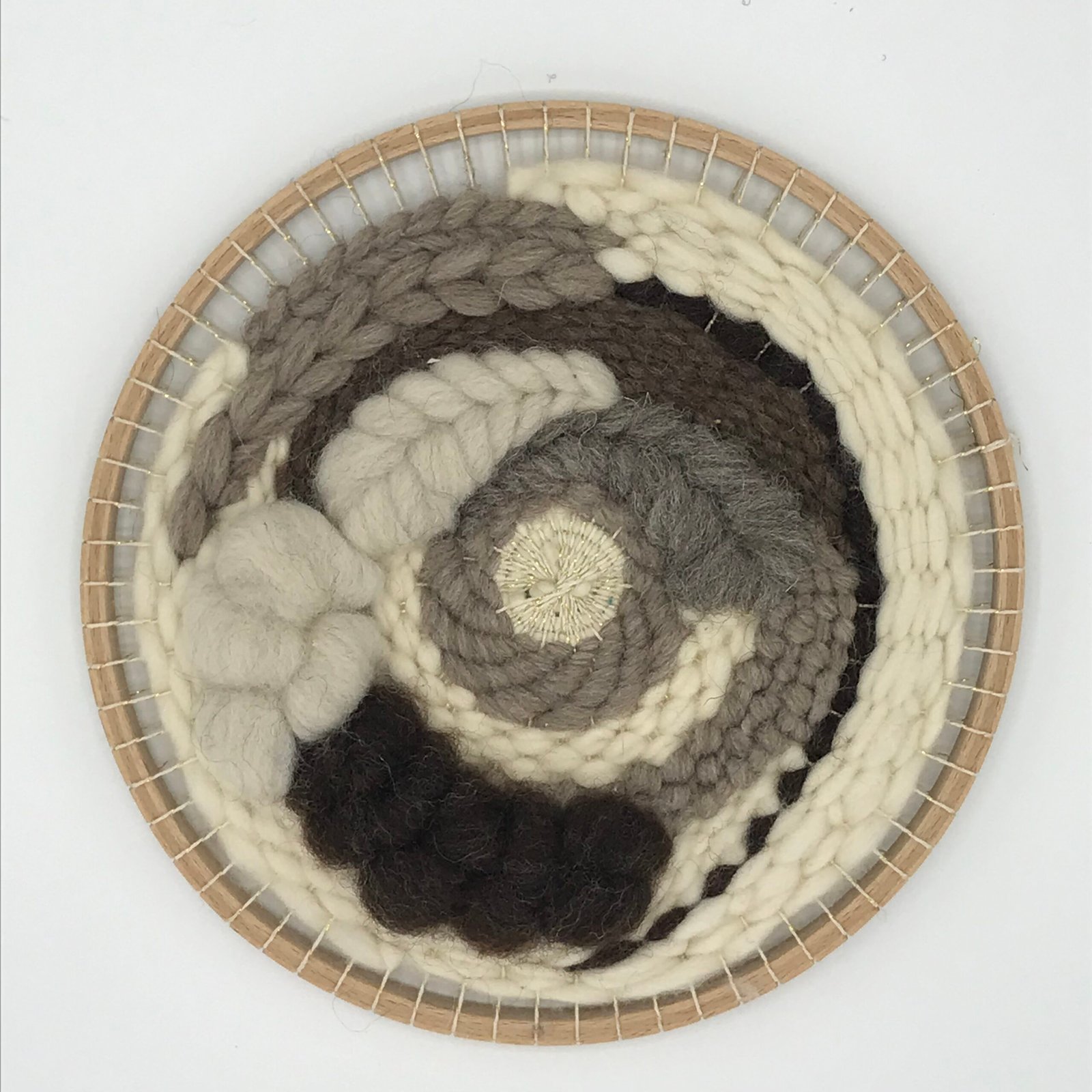 Ronde geweven wanddecoratie in warme aardtinten van wol, gemaakt met het weefpakket Natuurtinten van MaakTzelf.