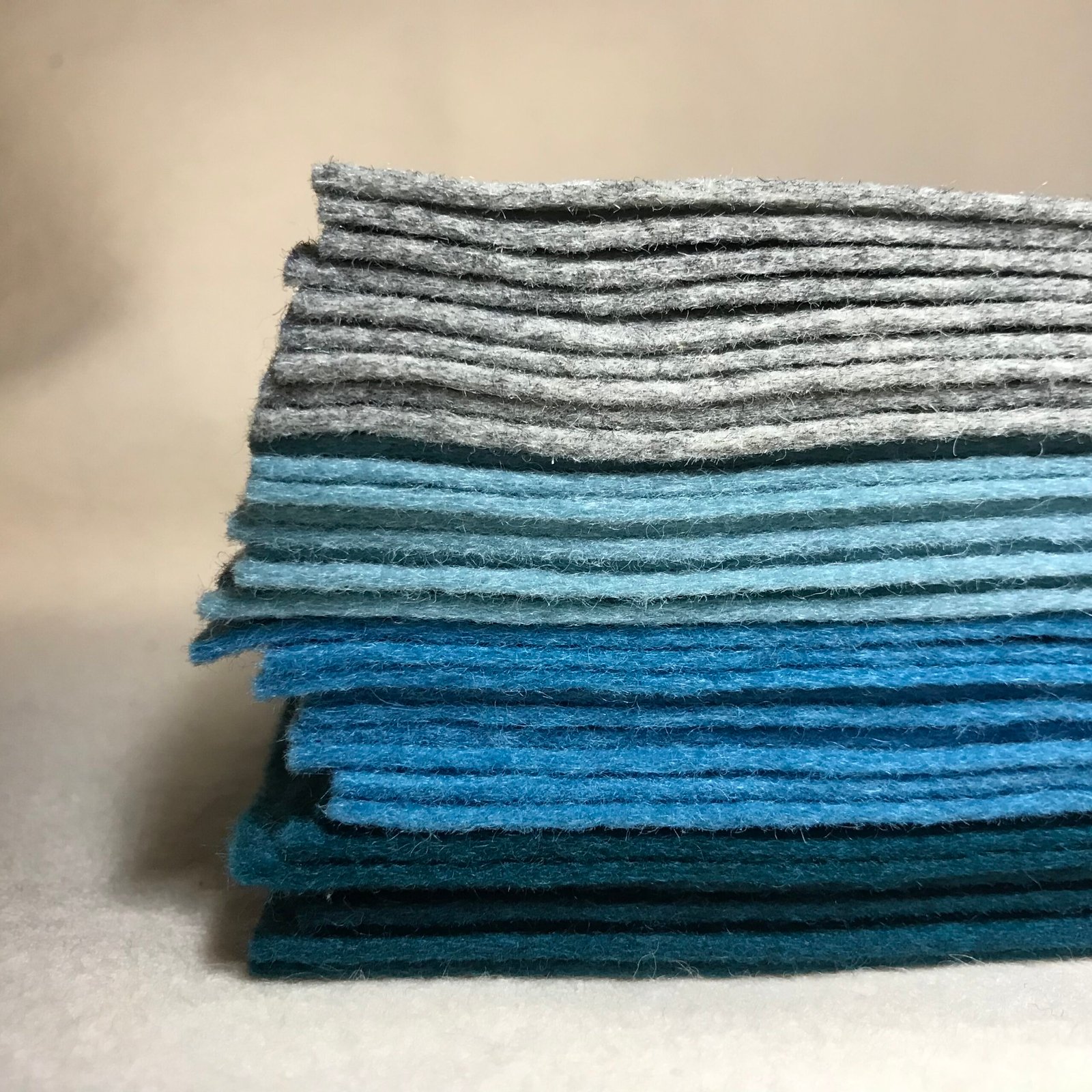 Blauw en grijs wolvilt in verschillende tinten, gebruikt voor het MaakTzelf Luchtballon Mobiel Blauw DIY-pakket.