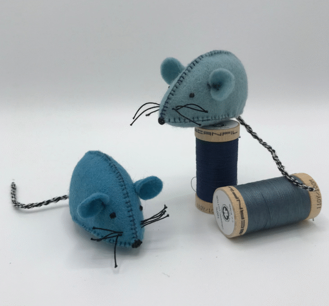 Twee blauwe wolvilt muisjes, waarbij er 1 op een blauw klosje garen zit, met een witte achtergrond