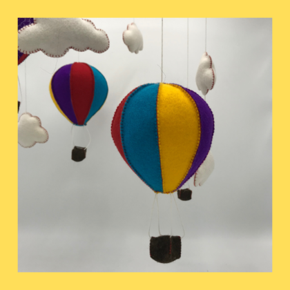 Een kleurige luchtballon gemaakt van wolvilt met wolkjes eromheen. Onderdeel van een mobiel voor in de kinderkamer.