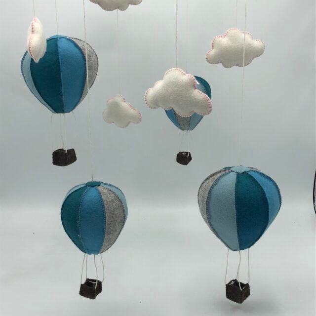 DIY viltpakket met blauwe en grijze luchtballonnen en witte wolkjes, hangend als mobiel van MaakTzelf.